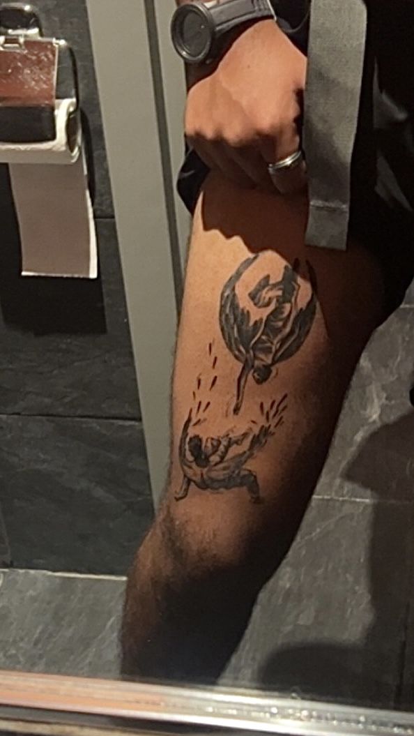 a man with a tattoo on his leg is standing in front of a bathroom mirror