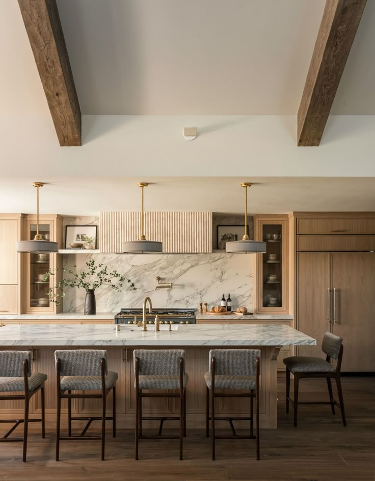 a large kitchen with marble counter tops and wooden beams on the ceiling, along with four chairs