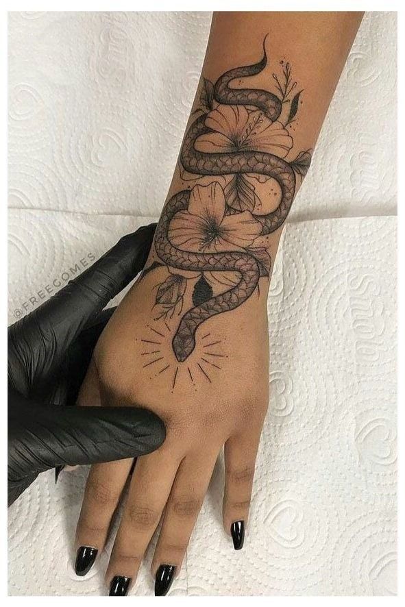 a woman's hand with a tattoo on it and a snake wrapped around the wrist