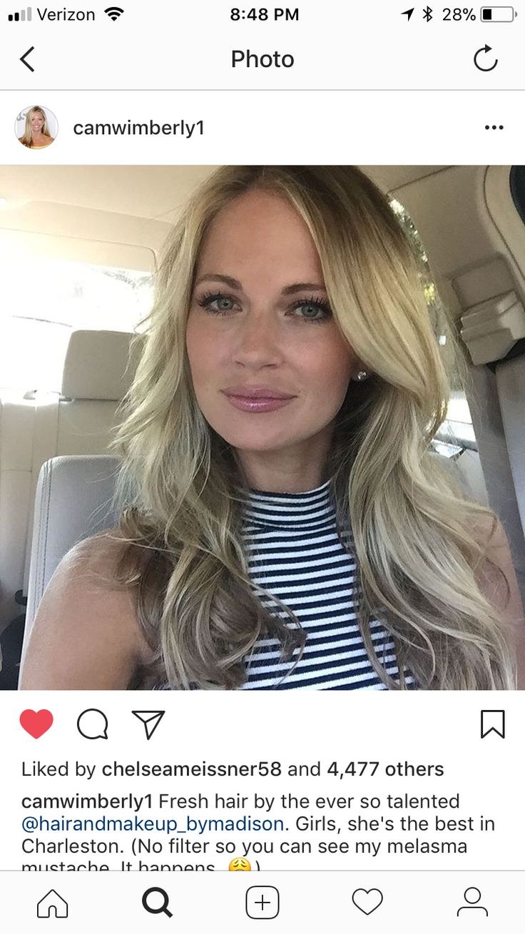 a woman with long blonde hair sitting in the back seat of a car and looking at the camera