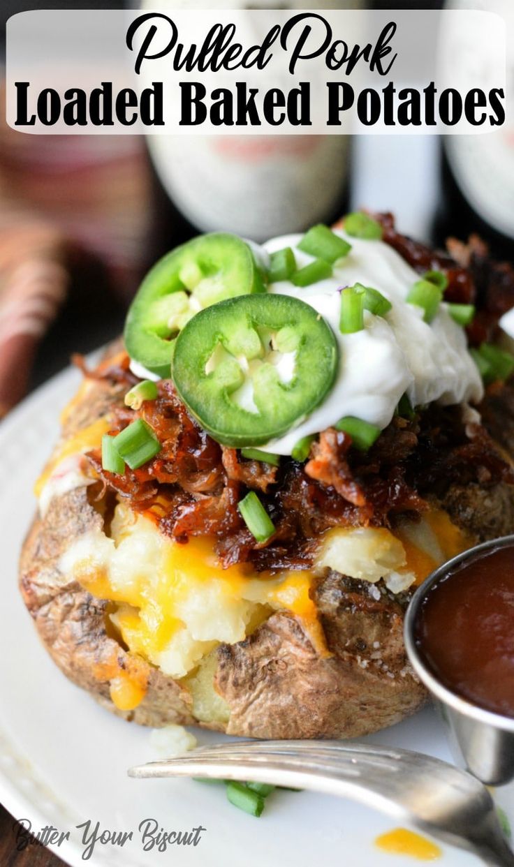 a loaded baked potato sitting on top of a white plate next to a bowl of sauce