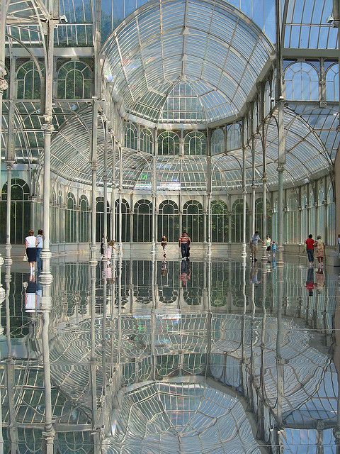 several people are standing in the middle of a building with many glass walls and windows