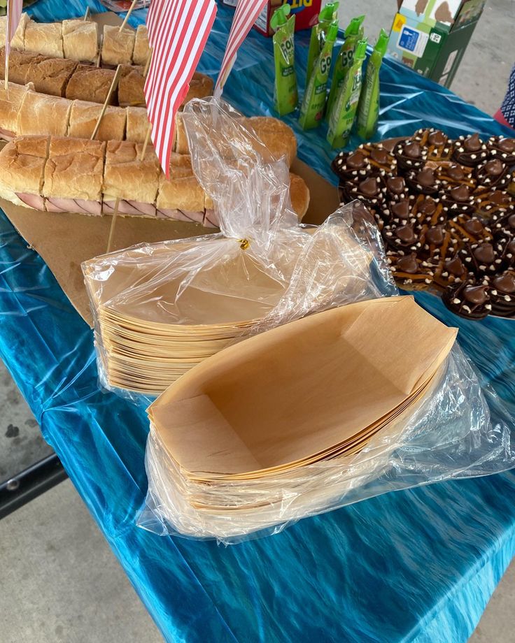 a table topped with lots of different types of sandwiches and pretzels on buns