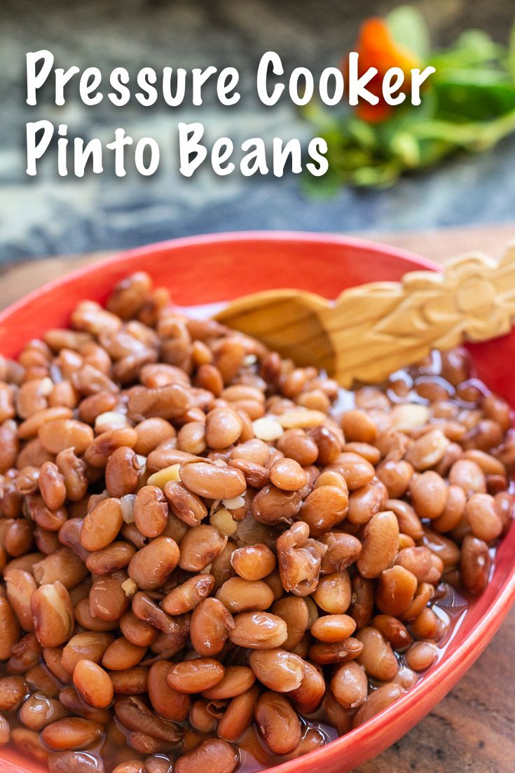 pressure cooker pinto beans in a red bowl with a wooden spoon on the side