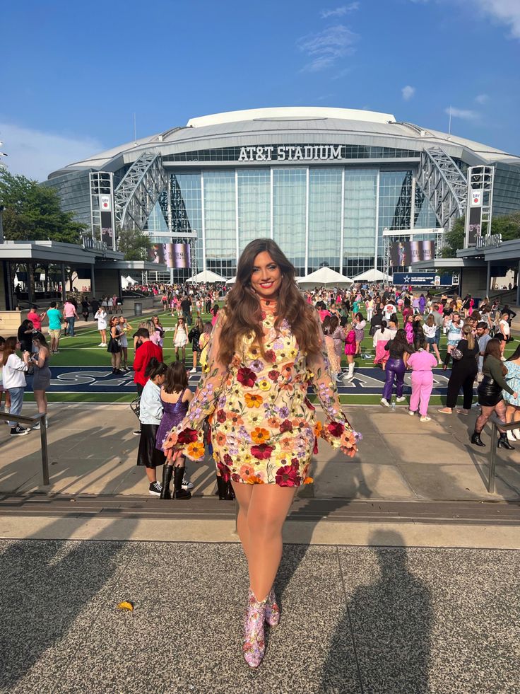 a woman in a floral dress is posing for a photo at the stadium with her legs spread out