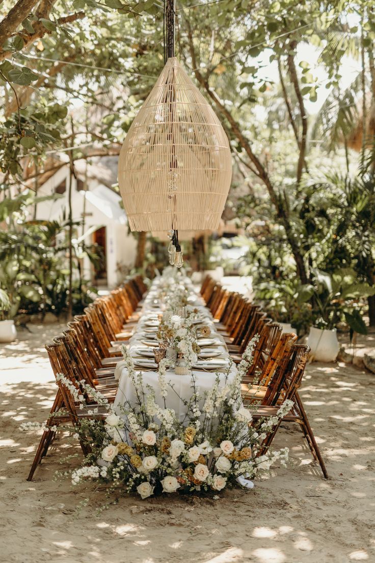 a long table is set up with white flowers and greenery for an outdoor dinner