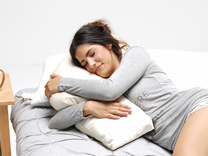 a woman laying on top of a bed with pillows