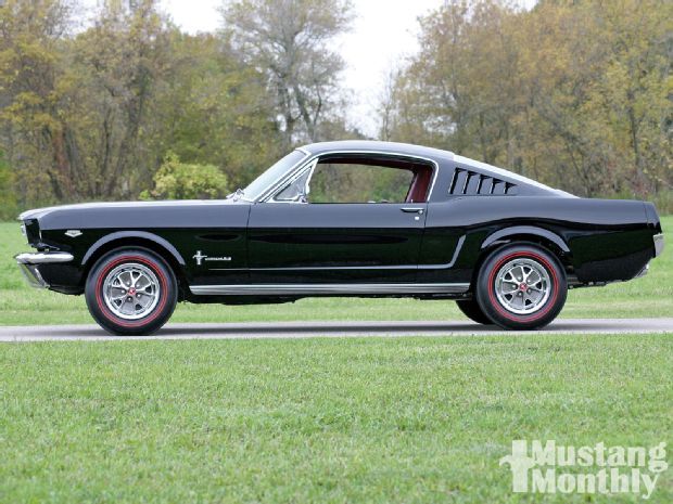 an old black mustang sitting on top of a grass covered field