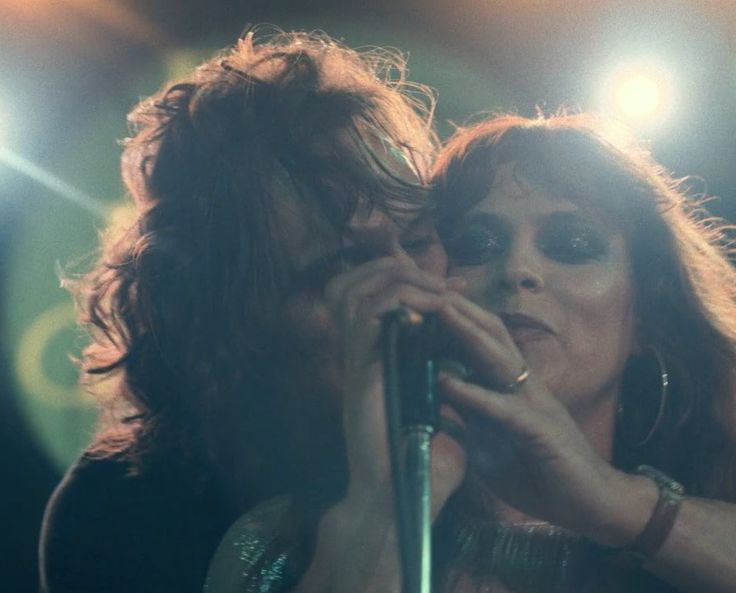 a man and woman standing next to each other holding microphones in their hands on stage