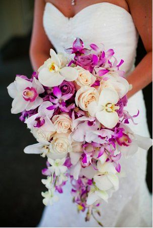 a bride holding a purple and white bouquet