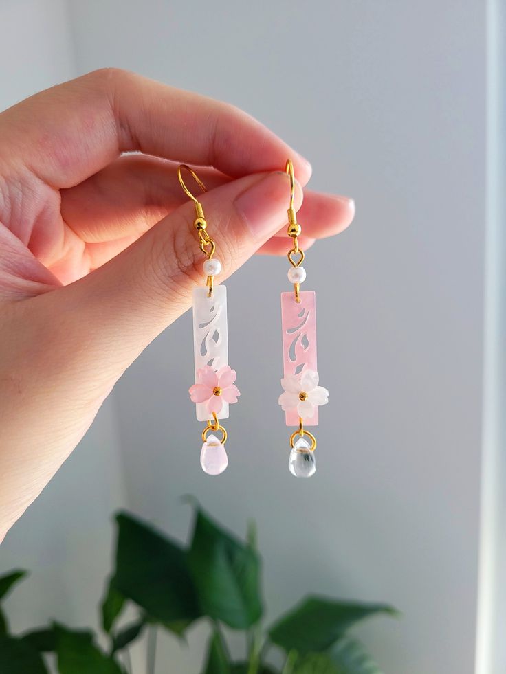 "Add something extra to your outfits with these dainty wind chime sakura earrings! Made with gold plated wire and resin. The dangle length is around 6.5cm/2.5\". Each pair is lovingly handmade! 🎀 CARE INSTRUCTIONS 🎀 * Avoid getting your jewelry wet * Avoid perfumes or sprays * Store in a cool, dry place" Sakura Wind Chime, Wind Chime Earrings, Sakura Jewelry, Fun Earrings Unique, Subtle Earrings, Wire And Resin, Sakura Earrings, Chinese Earrings, Cherry Blossom Jewelry