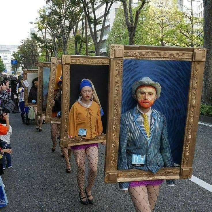 people are walking down the street with paintings on their backs and in front of them