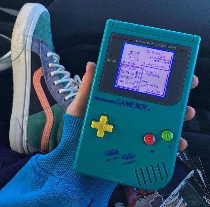 a person holding an old gameboy in their hand with the screen turned blue and yellow