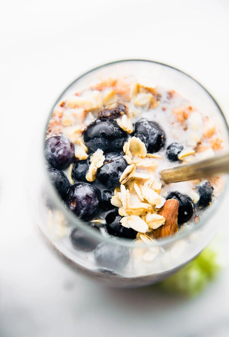 a glass filled with yogurt and blueberries on top of a white table