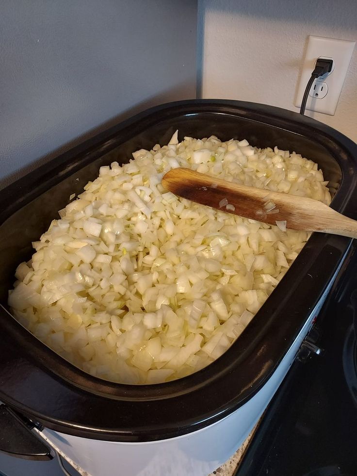 the food is being cooked in the crockpot on the stove top with a wooden spoon