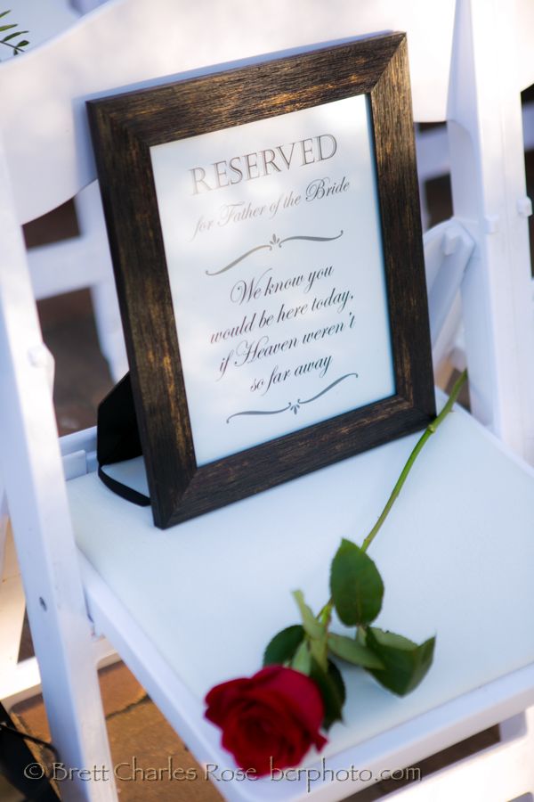 a red rose sitting on top of a white chair next to a framed sign that says reserved