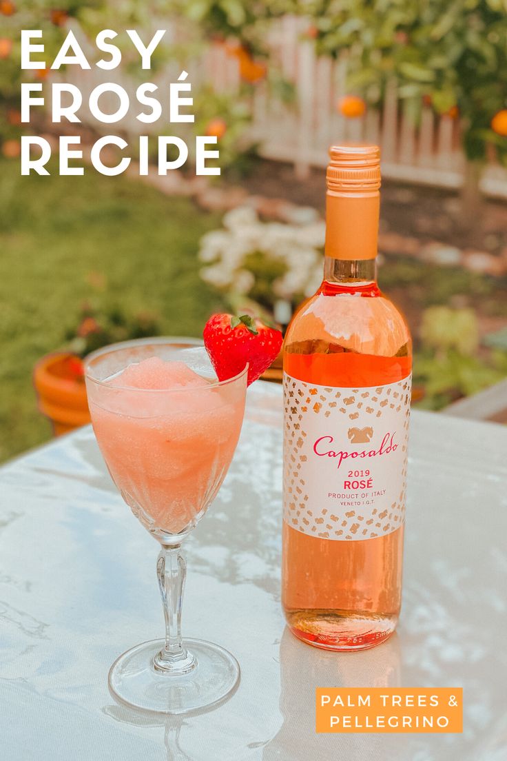 a bottle of pink wine and a glass on a table with a strawberry in it