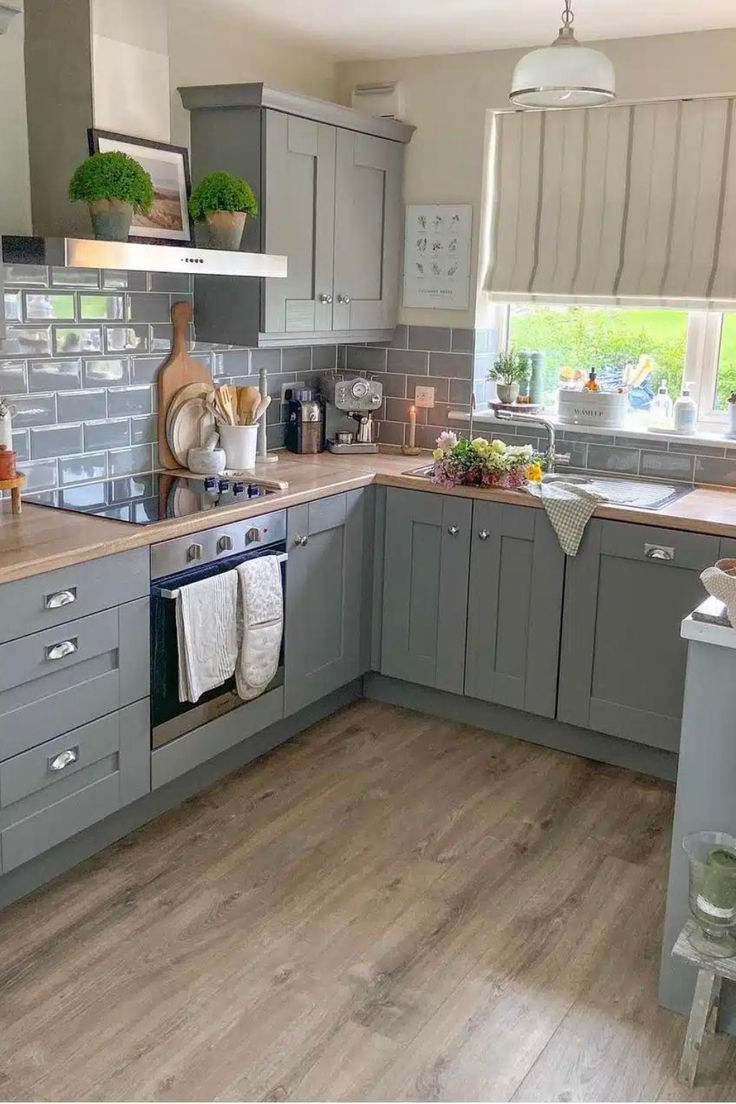 a kitchen with gray cabinets and wooden floors