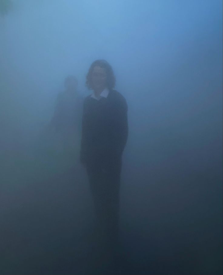 a man standing in the fog with his hands on his hips