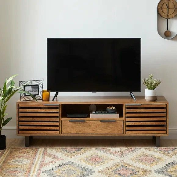 a flat screen tv sitting on top of a wooden entertainment center next to a potted plant