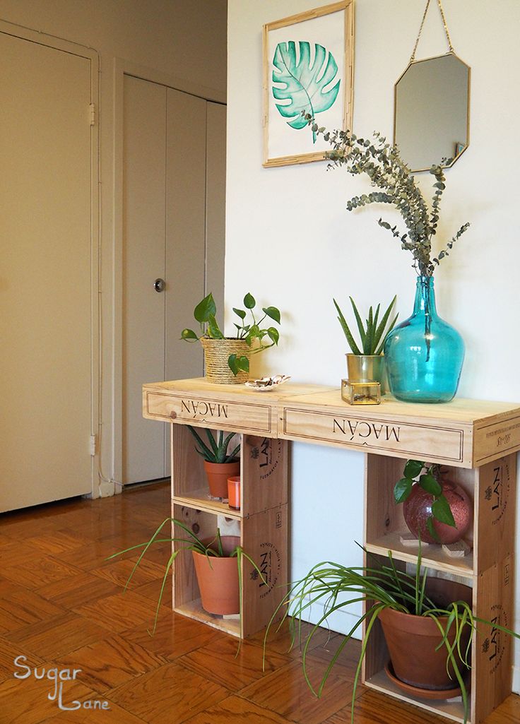 two wooden shelves with plants on them in front of a white wall and wood floor