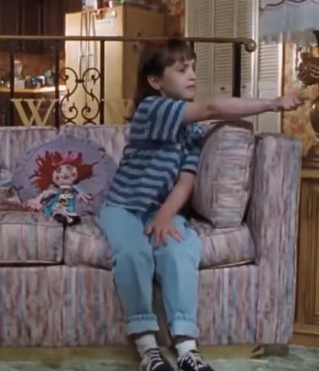 a young boy sitting on top of a couch in front of a tv screen with his arm out