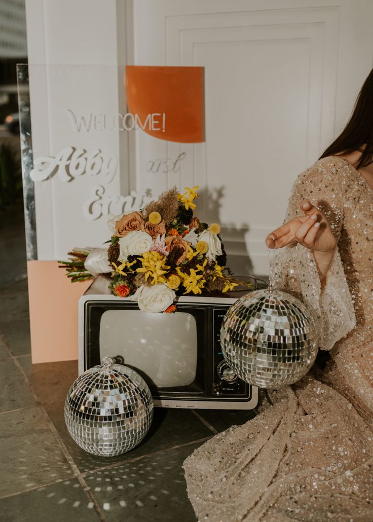 a woman sitting on the ground in front of a tv with disco balls around her