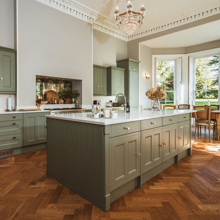 a large kitchen with wooden floors and green cabinets in the center, along with a chandelier hanging from the ceiling