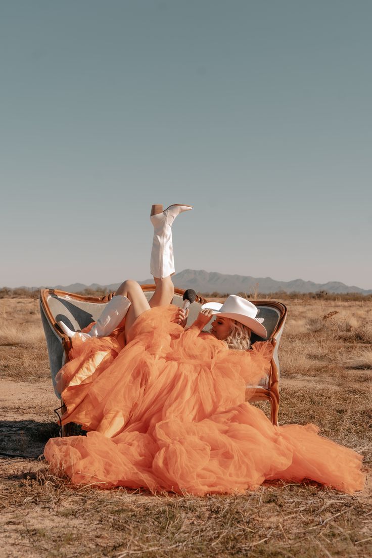 a woman laying on top of a couch in the middle of an open desert field