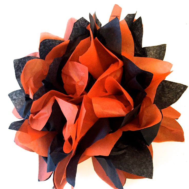 an orange and black paper flower on a white background