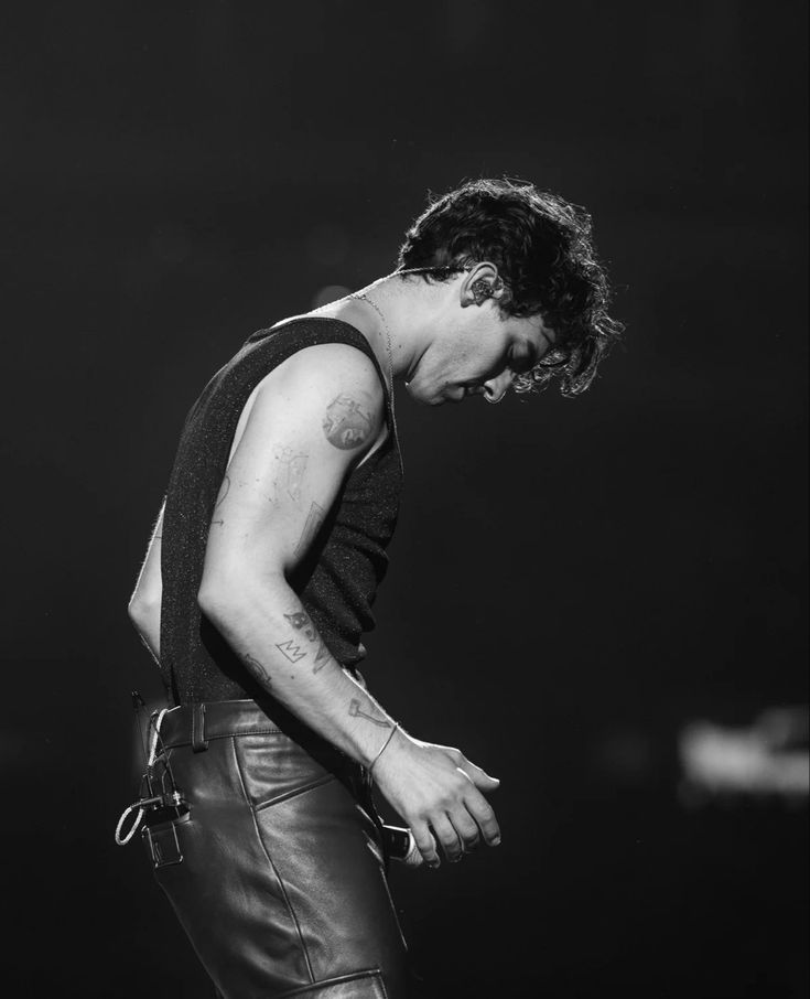 a black and white photo of a man in leather pants