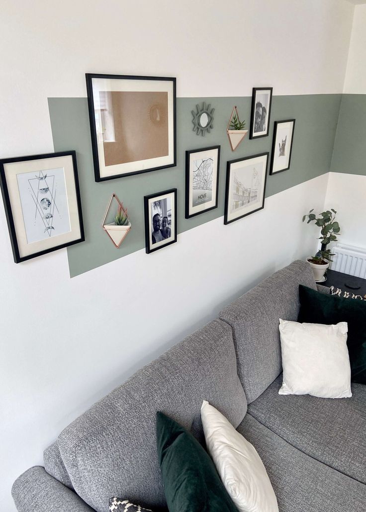 a grey couch with many framed pictures on the wall