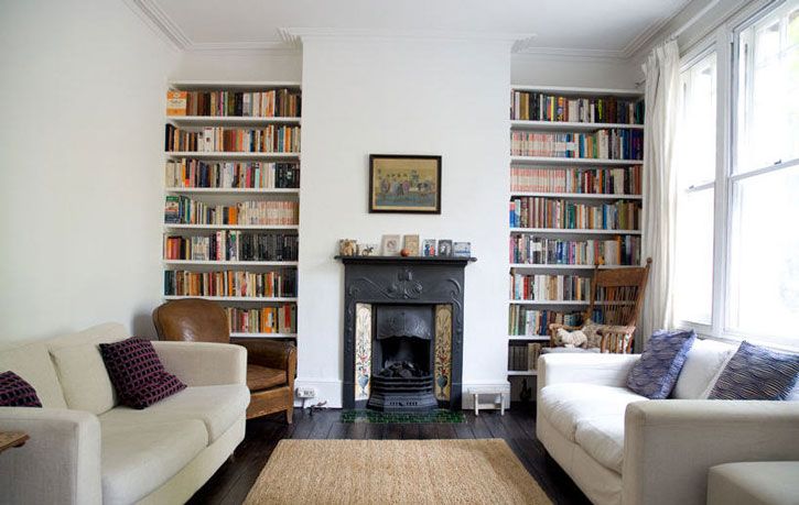 a living room filled with furniture and a fire place in front of a bookshelf