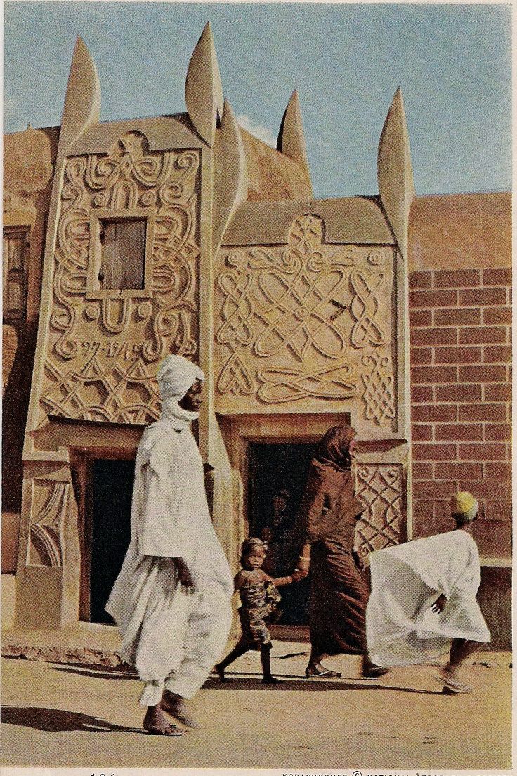 two men and a child are walking in front of an intricately carved building with arches