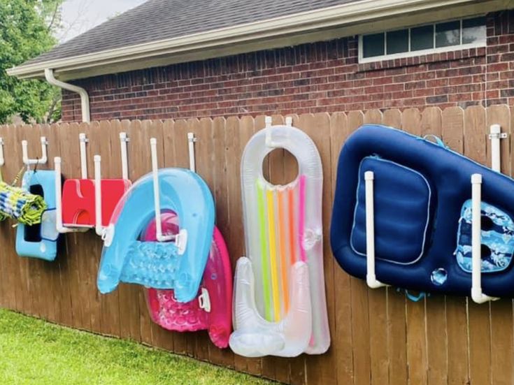 there are many different items hanging on the fence outside, including an inflatable pool