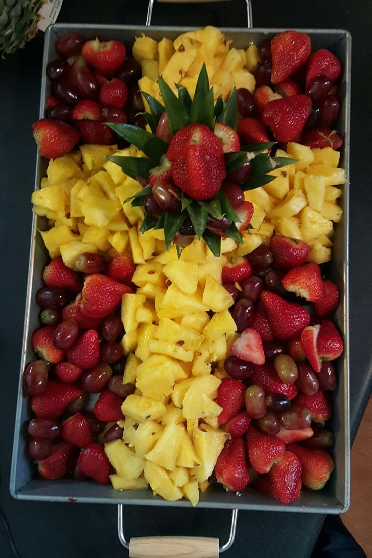 a tray filled with lots of fruit on top of a wooden table next to a pineapple