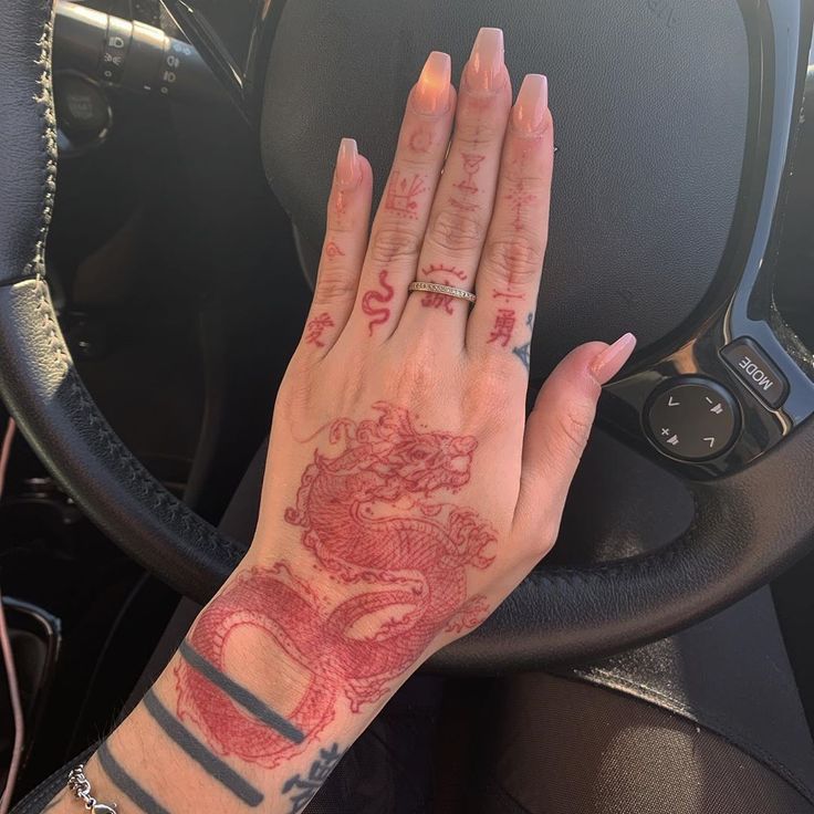 a woman's hand on the steering wheel of a car, with tattoos on it