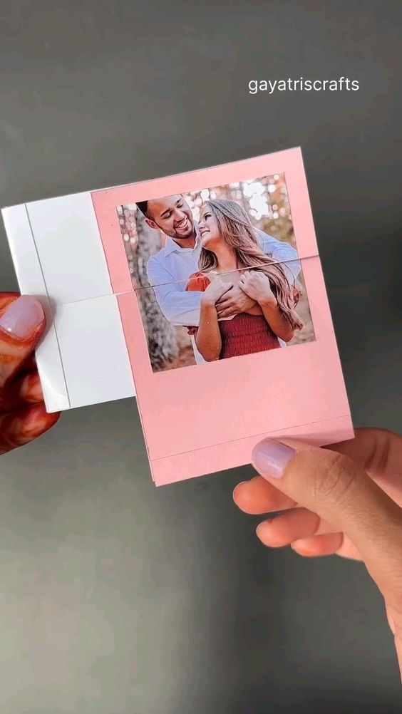 a person holding up a pink card with an image of two people in the background