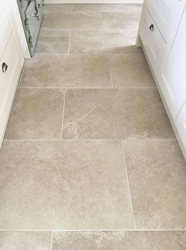 a kitchen with white cabinets and tile flooring