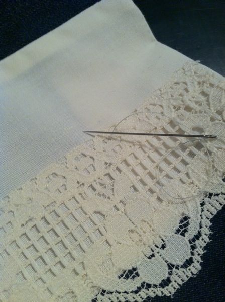 a pair of scissors cutting fabric on top of a piece of white paper with crochet lace