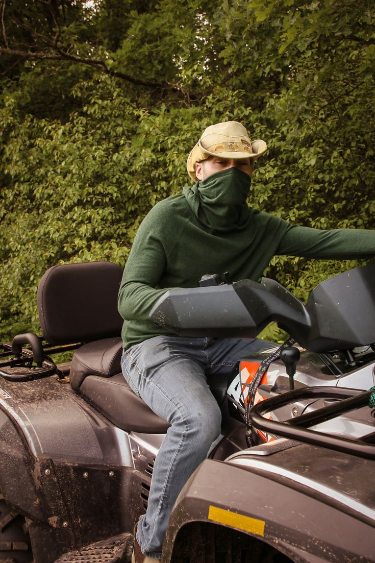 a man riding on the back of an atv with trees in the background and bushes behind him