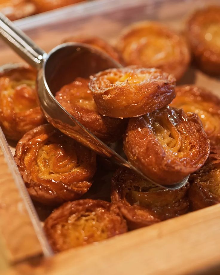 a wooden tray filled with pastries on top of a table next to a metal spoon