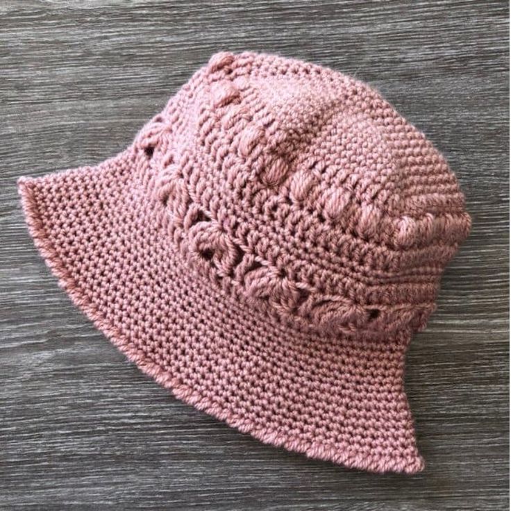 a pink knitted hat sitting on top of a wooden table