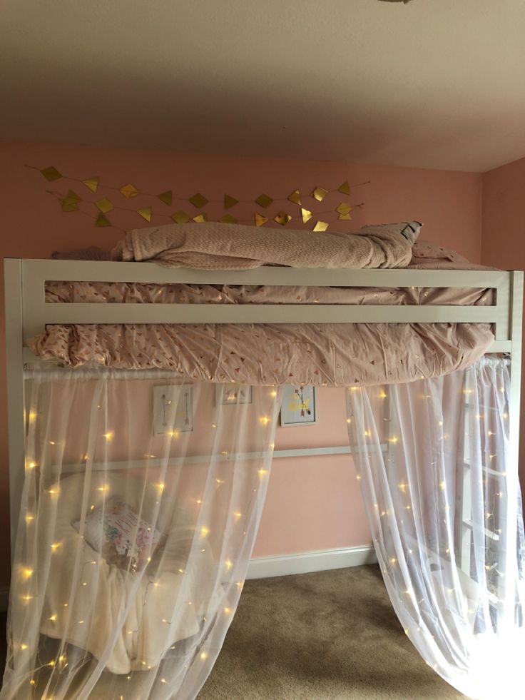 a bed with white curtains and lights on the bottom bunk, in a pink room