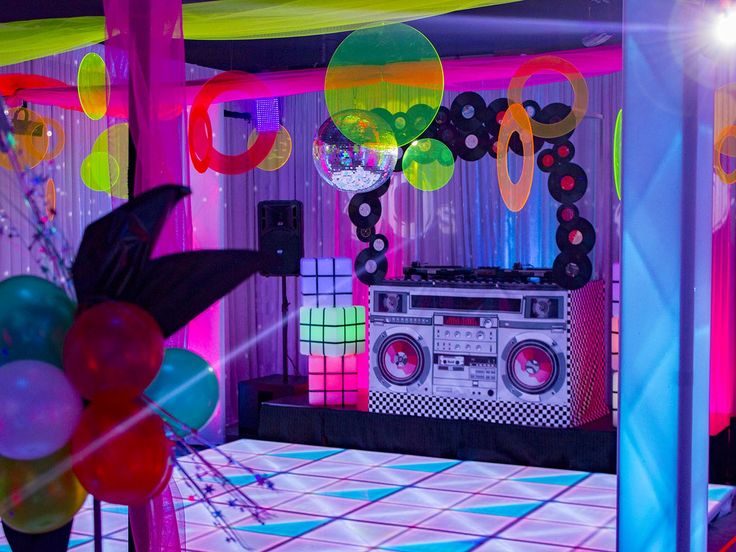 a party room decorated with balloons, disco balls and boombox in the middle of the dance floor