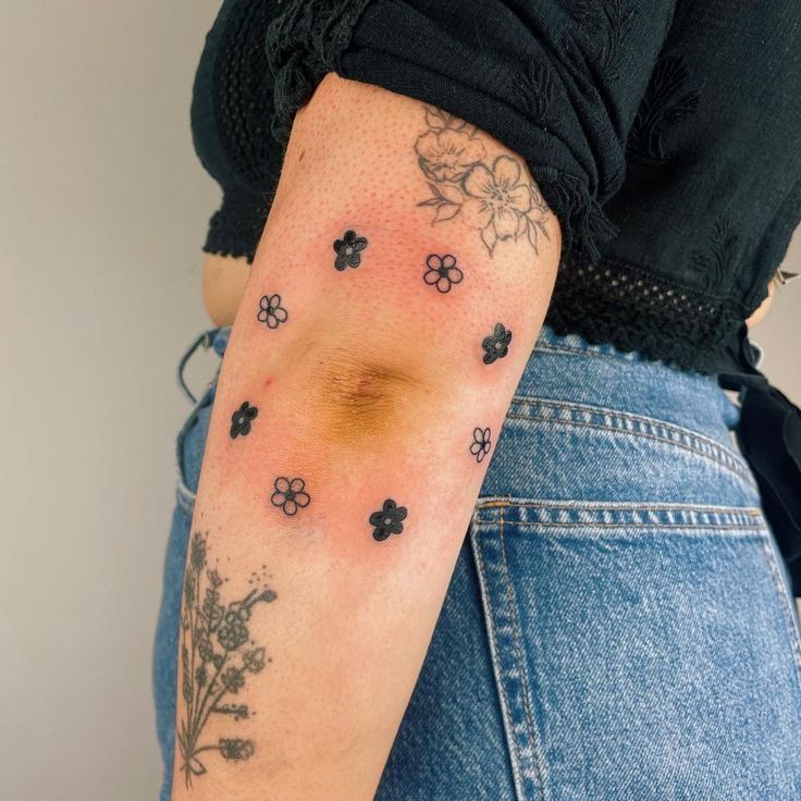 a woman's arm with tattoos on it and flowers in the middle of her arm