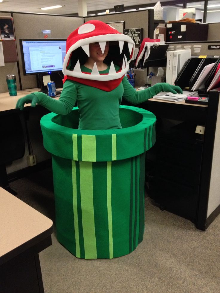 an office cubicle with a person dressed as a green monster sitting in a trash can