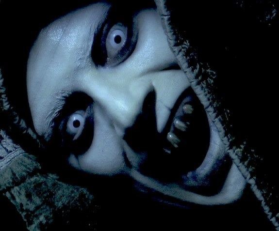 a creepy looking person with black eyes and white make - up looks at the camera