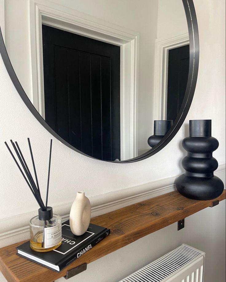 Hallways decor: neutral wall colours with large round black mirror above a wooden shelf styled with a black vase, book and simple reed diffuser. Neutral Hallway, Black Hallway, Hallway Inspiration, Home Ac, Hallway Decor, Neutral Walls, Black Accessories, Neutral Decor, Hallway Decorating