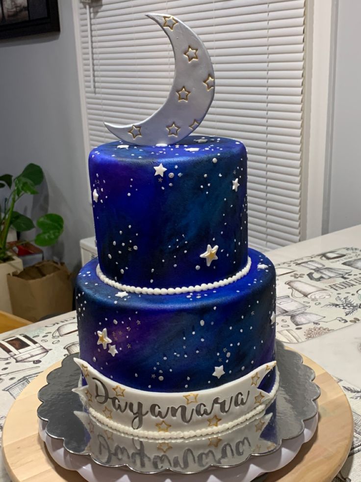 a three tiered cake decorated with stars and the moon